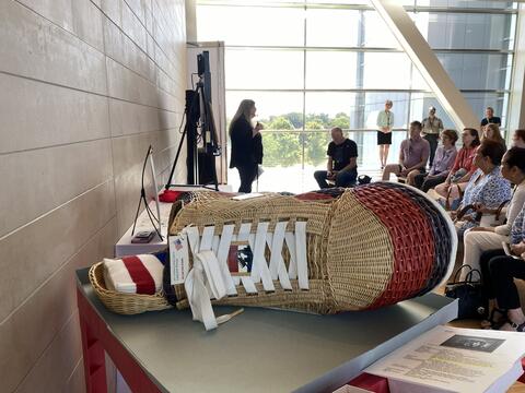 A large, detailed basket woven into the shape of a high-top sneaker sits on display during a presentation.