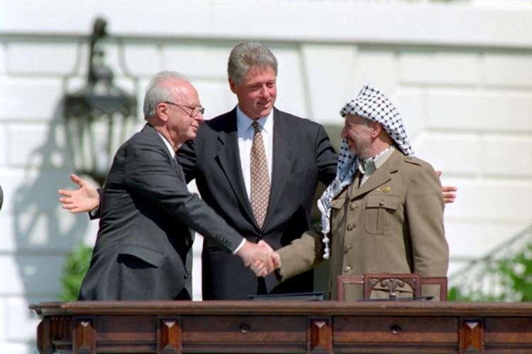 President William J. Clinton presiding over the handshake of Israeli Prime Minister Yitzhak Rabin and Palestinian Liberation Organization (PLO) Chairman Yasser Arafat during the Middle East Peace Agreement signing ceremony. The ceremony was on the South Lawn of the White House