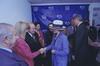 Bill Clinton stands to the right, engaged in conversation with other guests. Hillary Rodham Clinton wears a blue-and-white checkered blazer and a large white hat with a black band, while Menem and the other men are in dark suits. In the background, a blue step and repeat banner is prominently displayed, featuring the WorldCupUSA94 and FIFA logos.