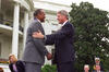 President Clinton stands with both hands of the arms of Harry Belafonte