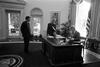 President Clinton meets with Director of the Office of Scheduling and Advance, Stephanie Streett, and President's Aide, Stephen Goodin in the White House Oval Office. Streett and Goodin stand in front of the President's desk. President Clinton sits, looking at a document on his desk 