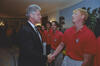President Bill Clinton shakes hands with a US soccer player wearing a red team polo shirt in the White House. Several other players stand in line behind him.