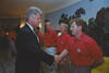 President Bill Clinton shakes hands with a US soccer team member wearing a red team polo shirt in the White House. Several other players stand in line behind him.