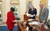 Meeting with the President in the Oval Office President Clinton, Minyon Moore, and Stephanie Streett stand while looking ad documents around the Resolute Desk in the Oval Office