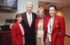 A photograph shows Bill Clinton posing with three women wearing matching red blazers and credentials around their necks, standing indoors with a television and buffet setup in the background.