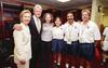 A photograph shows Hillary Clinton, Bill Clinton, and Chelsea Clinton smiling while posing in a locker room with three individuals wearing white United States Soccer Federation polo shirts and blue athletic shorts.