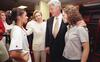 A photograph shows Hillary Clinton, Bill Clinton, and Chelsea Clinton interacting with Mia Hamm wearing a white jersey inside a locker room setting.