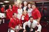A photograph shows Hillary Clinton, Bill Clinton, and Chelsea Clinton posing for a group photo inside a locker room with several staff members wearing matching red United States Soccer Federation polo shirts and jackets.