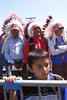 Event at the Pine Ridge Reservation Three Native Americans in ceremonial feathered headdresses and a young boy stand and listen a signing ceremony at the Pine Ridge Reservation in South Dakota. The boy stands behind a crowd control rail.