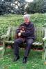 President William Jefferson Clinton holds Buddy the dog while sitting on a wooden bench