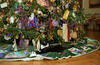 Socks the cat lays under the White House Christmas tree. The tree is decorated. Socks lays on a tree skirt.
