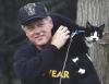 Socks the Cat sits on top of President Clinton's shoulder. The President scratches Socks. The President wears a city year sweatshirt and a baseball cap.