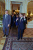 President Clinton walks and listens to President Václav Havel as the walk through Prague Castle. They are followed by a group of people including Madeleine Albright. Ther are in an elegant room with tiled floors and mirrored walls.