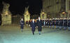 President Clinton and Václav Havel walk through the Matthias Gate in the courtyard of Prague Castle. The courtyard is flanked with members of the Prague Castle Guard standing at attention. The Photograph is taken and night. One of the "Giants" statues of the gate may be seen in the background.
