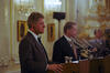 President Clinton and President Václav Havel stand,, next to each other behind, podiums. The podiums have microphones. Both men wear earphone headsets for translation. 