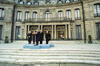 President Václav Havel stands behind a podium on a light blue stage. The stage sits on stone stairs. President Clinton, President Michal Kovac of Slovakia, President Lech Walesa of Poland, and President Arpad Goncz of Hungary stand behind President Havel. Petschek Villa, an opulent neo-baroque building with gilded doors and columns can be seen in the background.