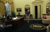 Chelsea Clinton holds Socks the Cat above her head while President Clinton works behind the Resolute Desk in the Oval Office of the White House