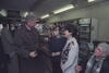 President Clinton talks to two women in a store. President Clinton and two women stand, and one woman sits, looking up.