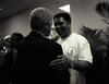 Black and white photo. President Clinton stands with his left hand on the shoulder of Muhammed Ali. Ali grips Clinton's rich arm with his left hand.