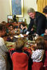 President Clinton leans over the Resolute desk in the Oval Office. Children surround the desk.