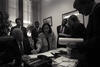 Black and white photograph. President Clinton sits at a desk. Speechwriter, June Shih leans over the desk to point at speech draft, President Clinton is looking down at the paper.