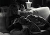 Camp David Black and white photograph. President Clinton reclines on a couch, with his head on a pillow, next to his daughter, Chelsea Clinton as she holds a television remote control.