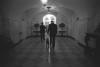 Black and White photograph. President Clinton walks, with Buddy the dog on a leash, down a hallway in the White House