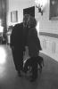 Black and white photograph. President Clinton kisses the First Lady, Hillary Rodham Clinton, in the White House as Buddy the Dog is at their feet