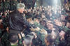 President Clinton stands elevated, looking down at the troops. The Troops look up reaching their hands toward President Clinton. President Clinton greets troops during his visit to Tuzla Air Force Base in Bosnia-Herzegovina.
