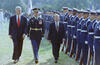 President Clinton, President Václav Havel, and unknown uniformed Army officer, walk on green grass on the South Lawn of the White house looking at a line of uniformed troops standing at attention in formation.