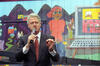 Plugged In Event President Clinton holds a hand held microphone. He stands in front of a brightly painted mural.