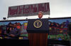 Plugged In Event President Clinton addresses attendees at an event hosted at Plugged In Enterprises as part of the third New Markets Tour. President Clinton stands behind a podium and Rev. Jesse Jackson sits in the background.