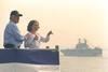 Independence Day President Clinton and daughter Chelsea Clinton stand on a dock in the New York Harbor. Chelsea points at U.S. and International warships in the harbor. President Clinton wears a baseball cap.