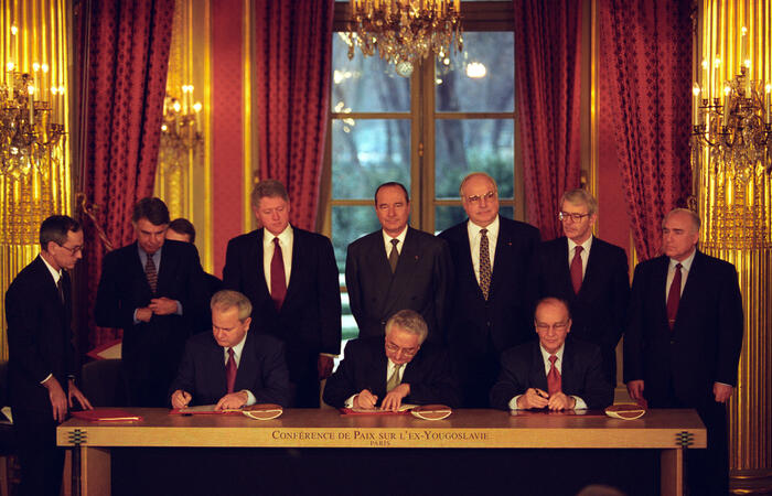 This item is a photograph of the Balkan Peace Agreement signing in Paris, France. President William Jefferson Clinton watches at President Slobodan Milosevic of Serbia, President Alija Izetbegovic of Bosnia, and President Franjo Tudjman of Croatia sign the treaty.