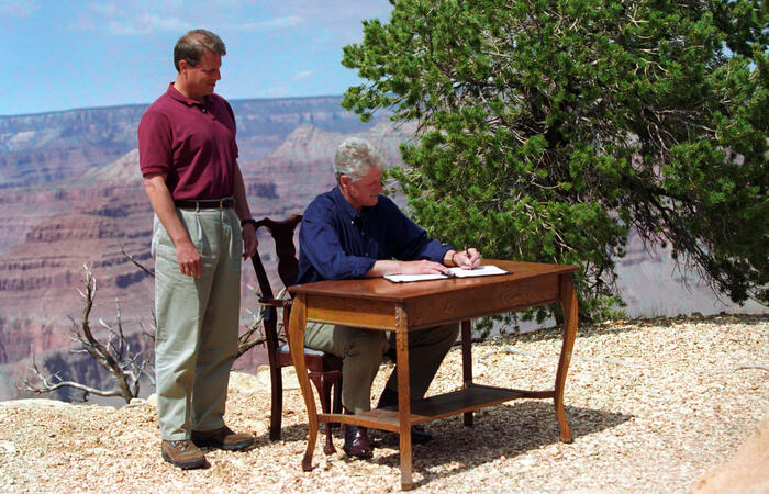 President Clinton signs Proclamation 6920, establishment of the Grand Staircase-Escalante National Monument at Grand Canyon National Park on September 18, 1996. Vice President Gore stands behind the President as he signs.
