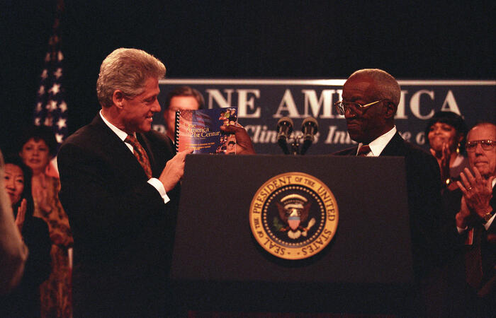 President Clinton holds up a report titled 'One America 2st Century' with historian, John Hope Franklin, at an event where the President addresses the President's Advisory Board on Race