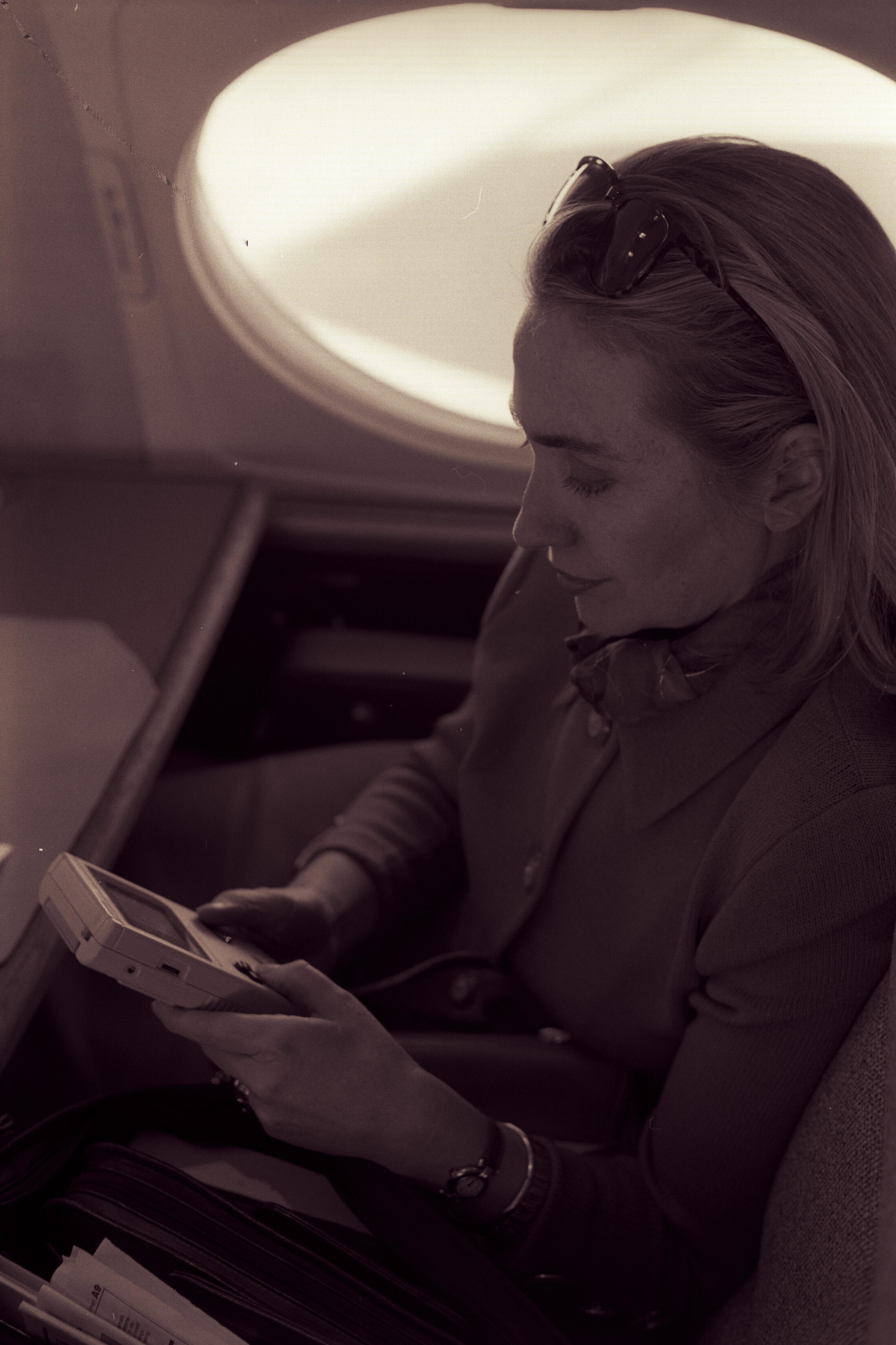 Black and White photograph. First Lady Hillary Rodham Clinton playing a Nintendo Game Boy on the flight from Austin Texas enroute to Washington, D.C. A