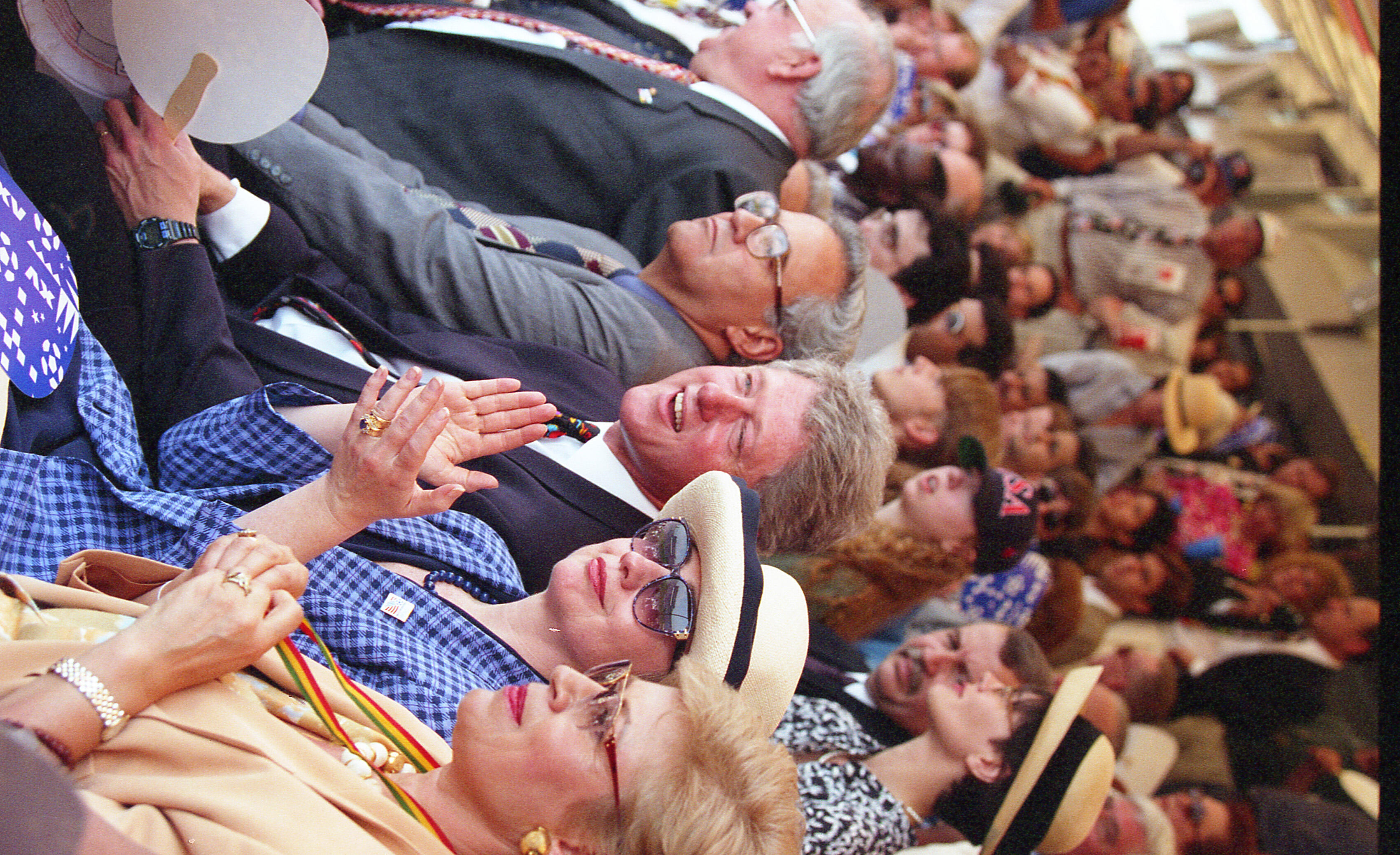 Helmut Kohl: The former Chancellor of Germany (partially visible on the far left). President Gonzalo Sánchez de Lozada of Bolivia wearing glasses and a gray suit. Bill Clinton: The 42nd President of the United States, seen laughing and gesturing toward the field. Hillary Rodham Clinton: The then-First Lady, wearing a blue checkered blazer, sunglasses, and a wide-brimmed cream hat. Ximena Iturralde: The wife of then-Bolivian President Gonzalo Sánchez de Lozada. She is wearing a tan blazer and a lanyard 