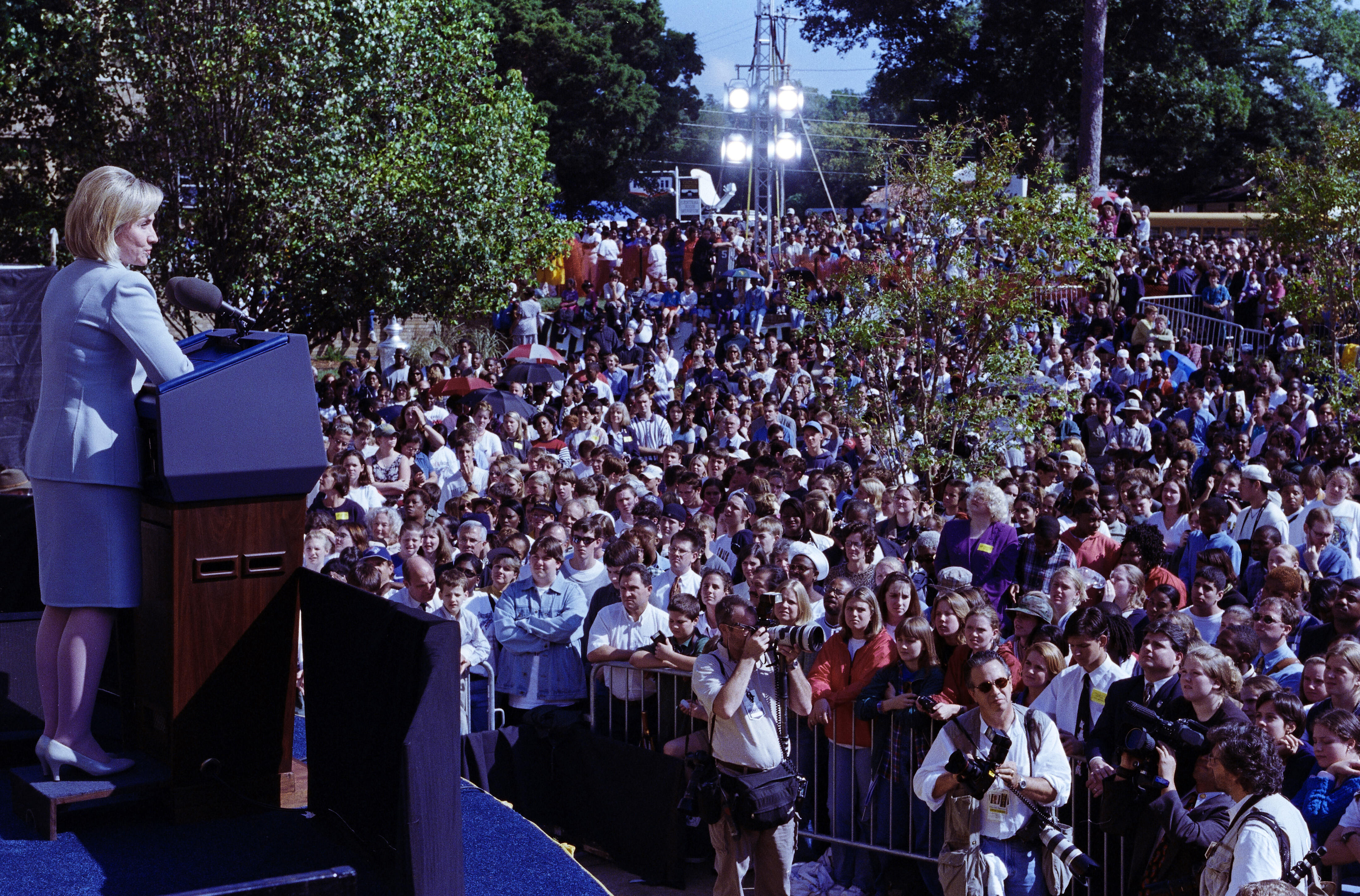 First Lady Hillary Rodham Clinton Stands on stage, behind a podium, looking down toward a crowd of people