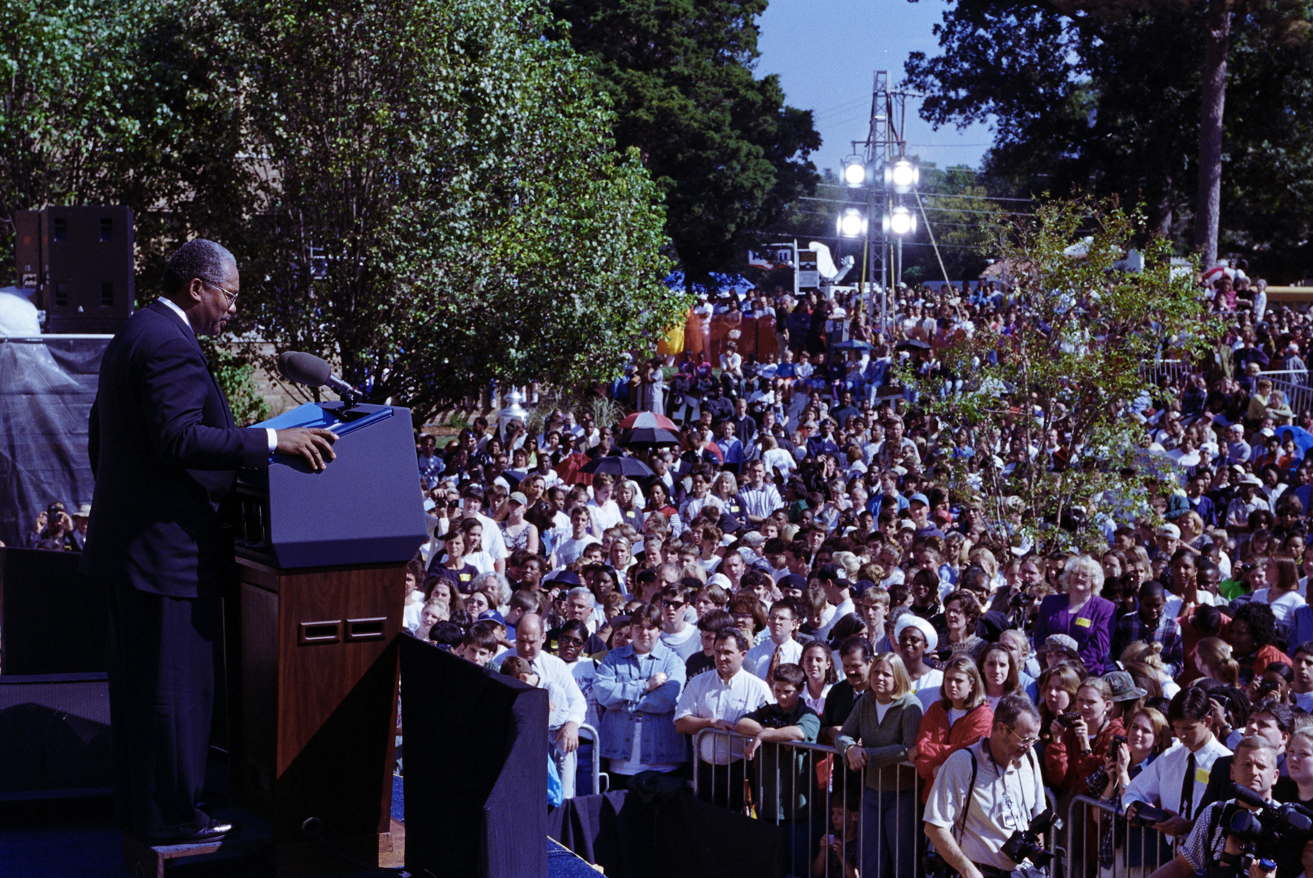Ernest Green stands on a stage, behind a podium, looking out toward a crowd of people