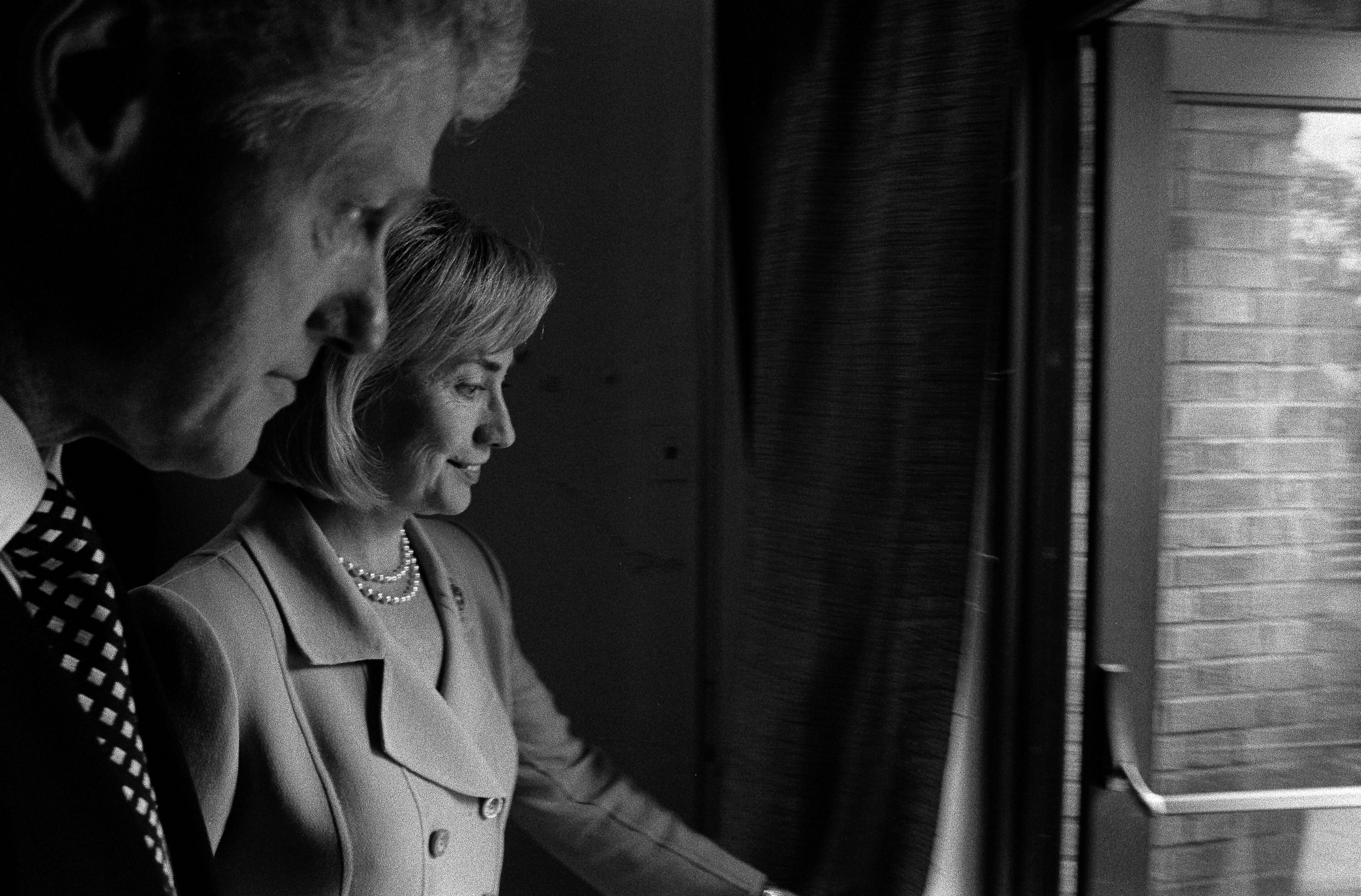 Black and white photograph. President Clinton and First Lady Hillary Rodham Clinton look out at the crowd through open doors.
