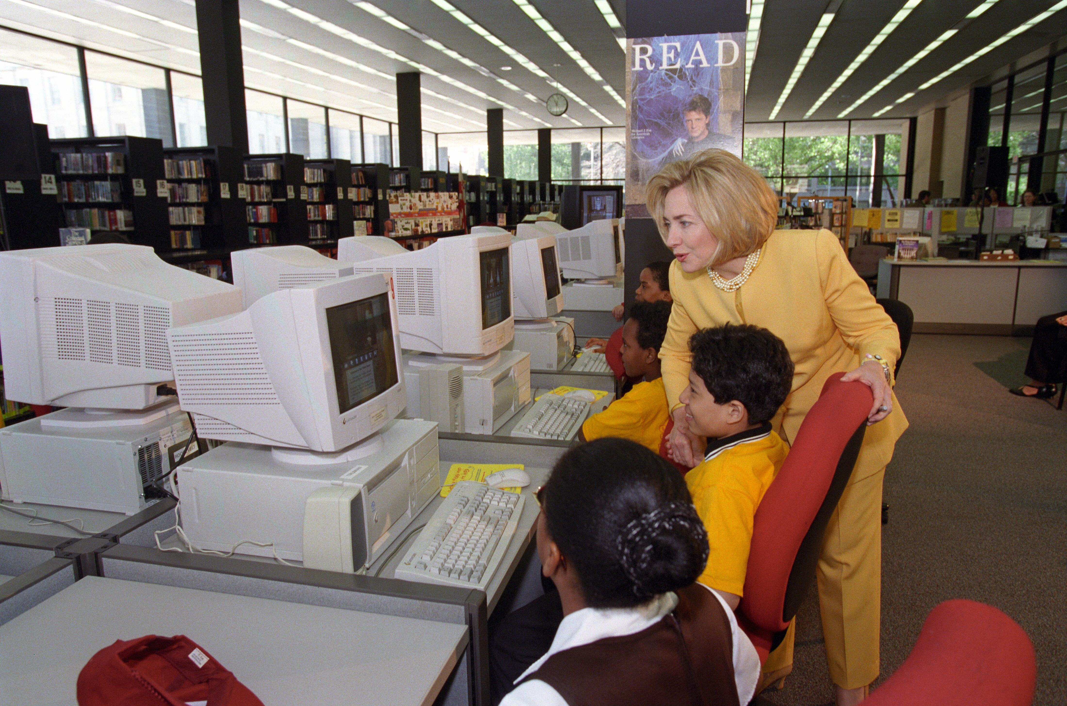 First Lady Hillary Rodham Clinton looks at a computer monitor and talks to students about the CD ROM and watches them work on computers at the Martin Luther King Library's "The White House is Our House" Event