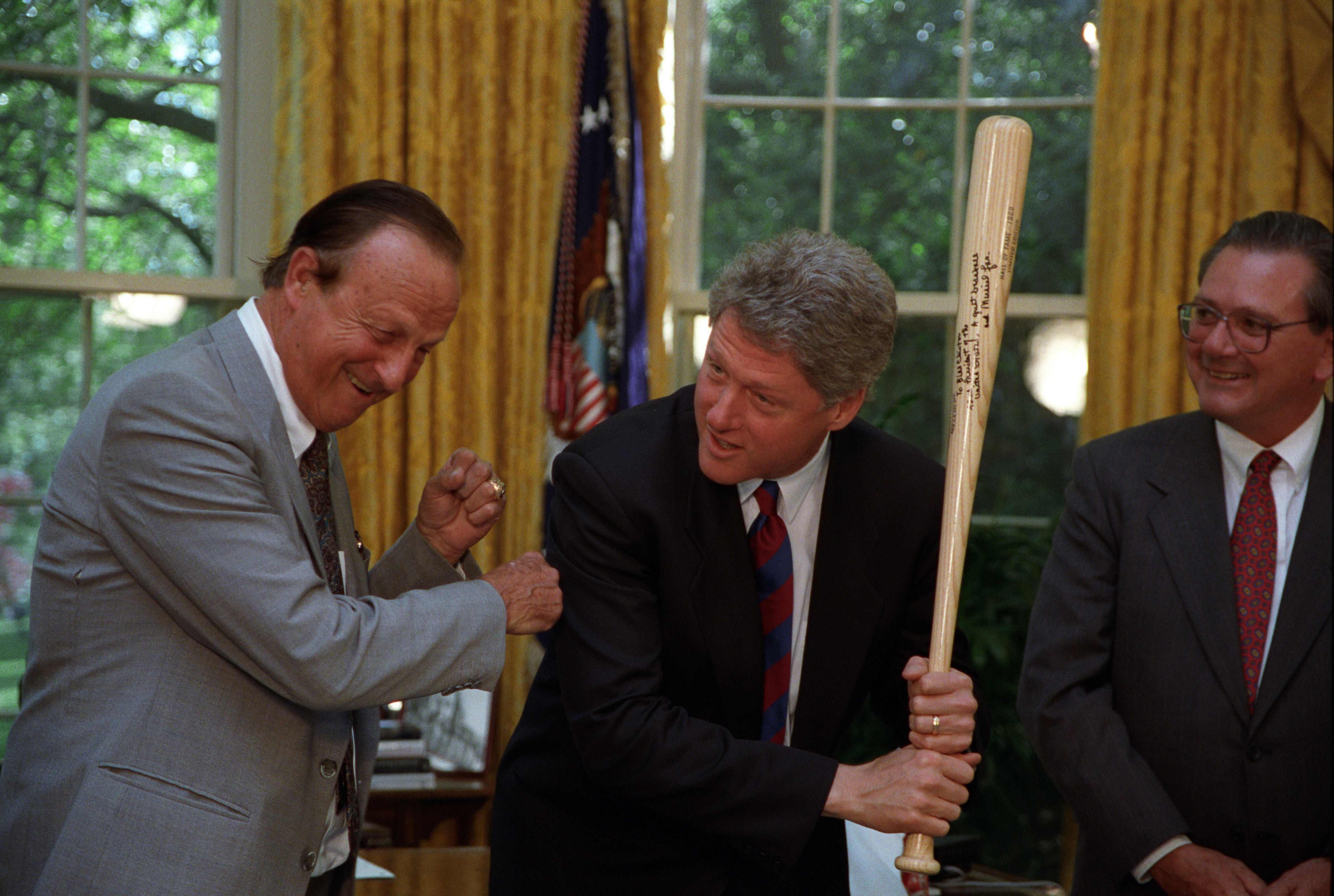 President Clinton poses with a baseball bat in the Oval Office after receiving it from St. Louis Cardinals Hall of Famer Stan Musial