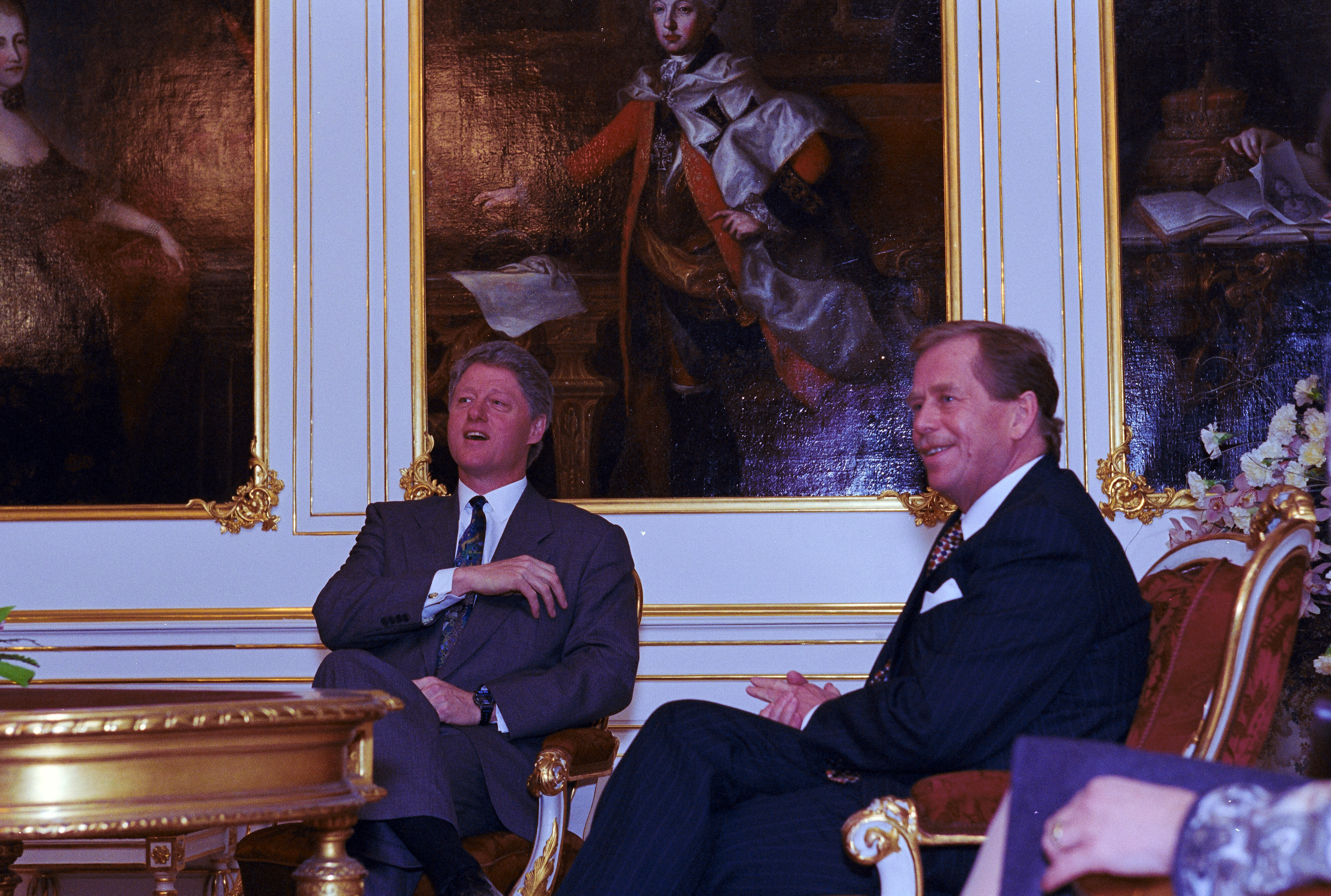 President Clinton sits with President Václav Havel. A painting of a person is on the wall behind President Clinton.