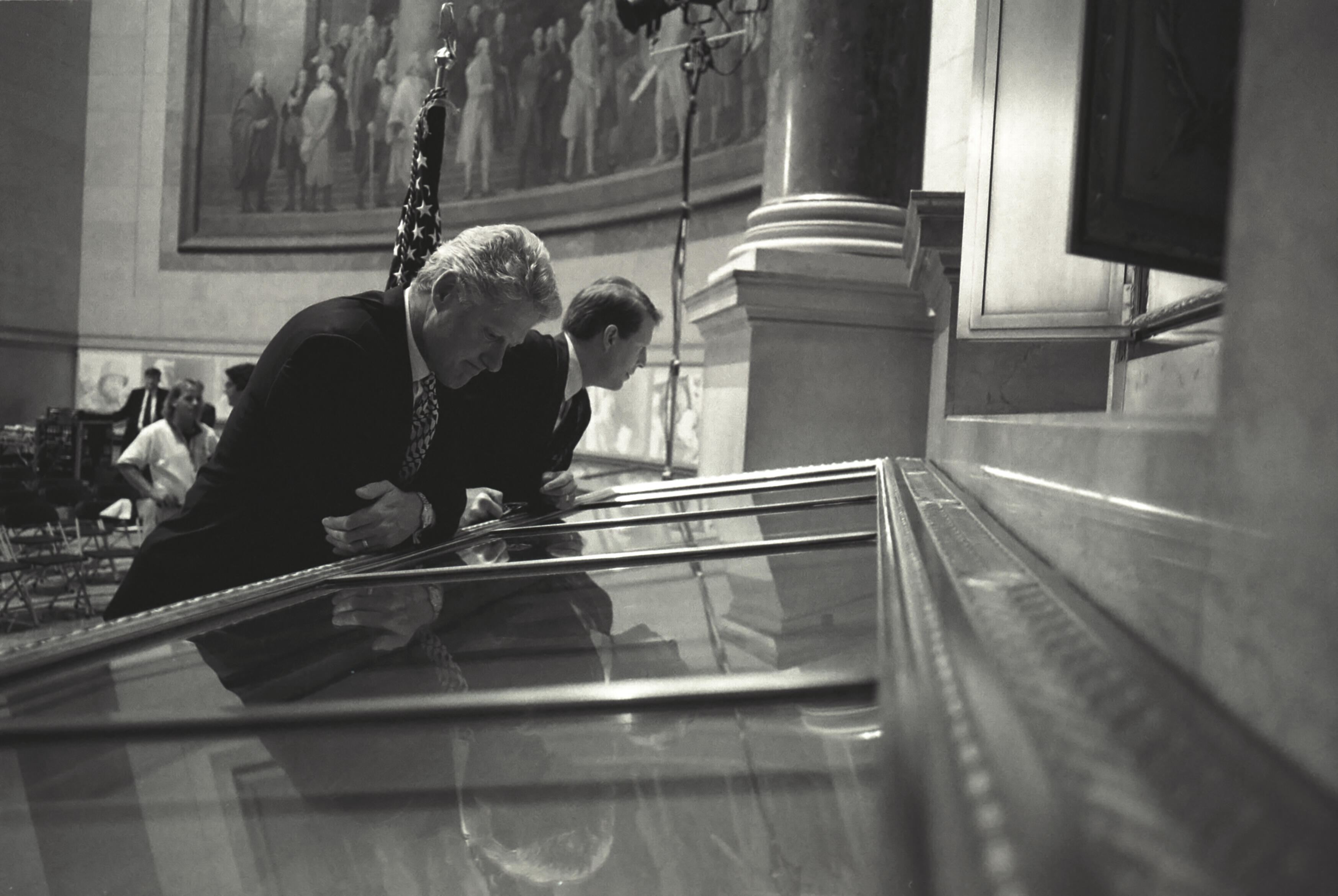 Black and white phtograph. President Clinton and Vice President Gore read the United States Constitution on display in the rotunda at the National Archives in Washington, D.C. prior to the President's speech on affirmative action.