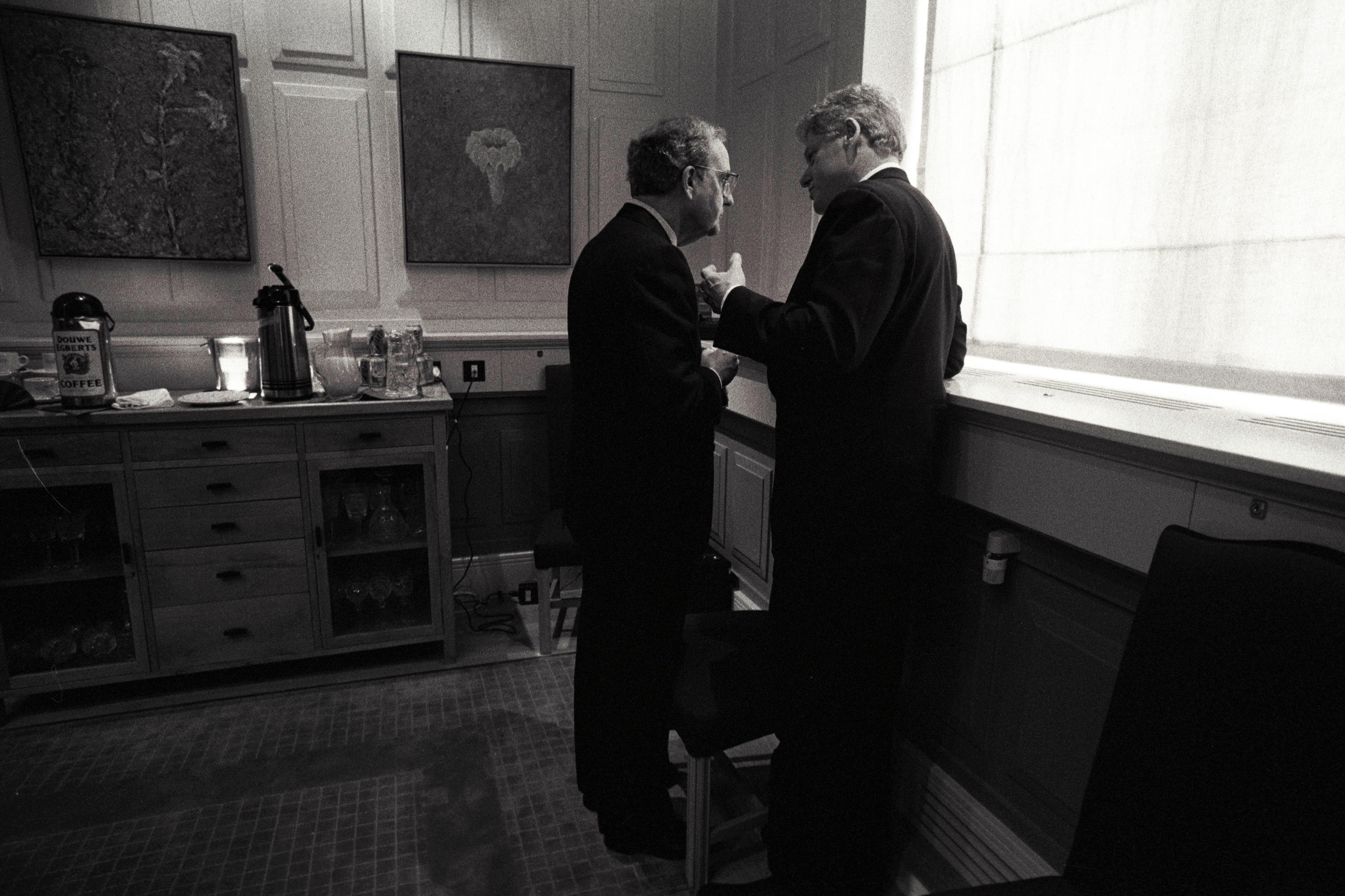Black and white photograph. President Clinton stands very close to Senator George Mitchell