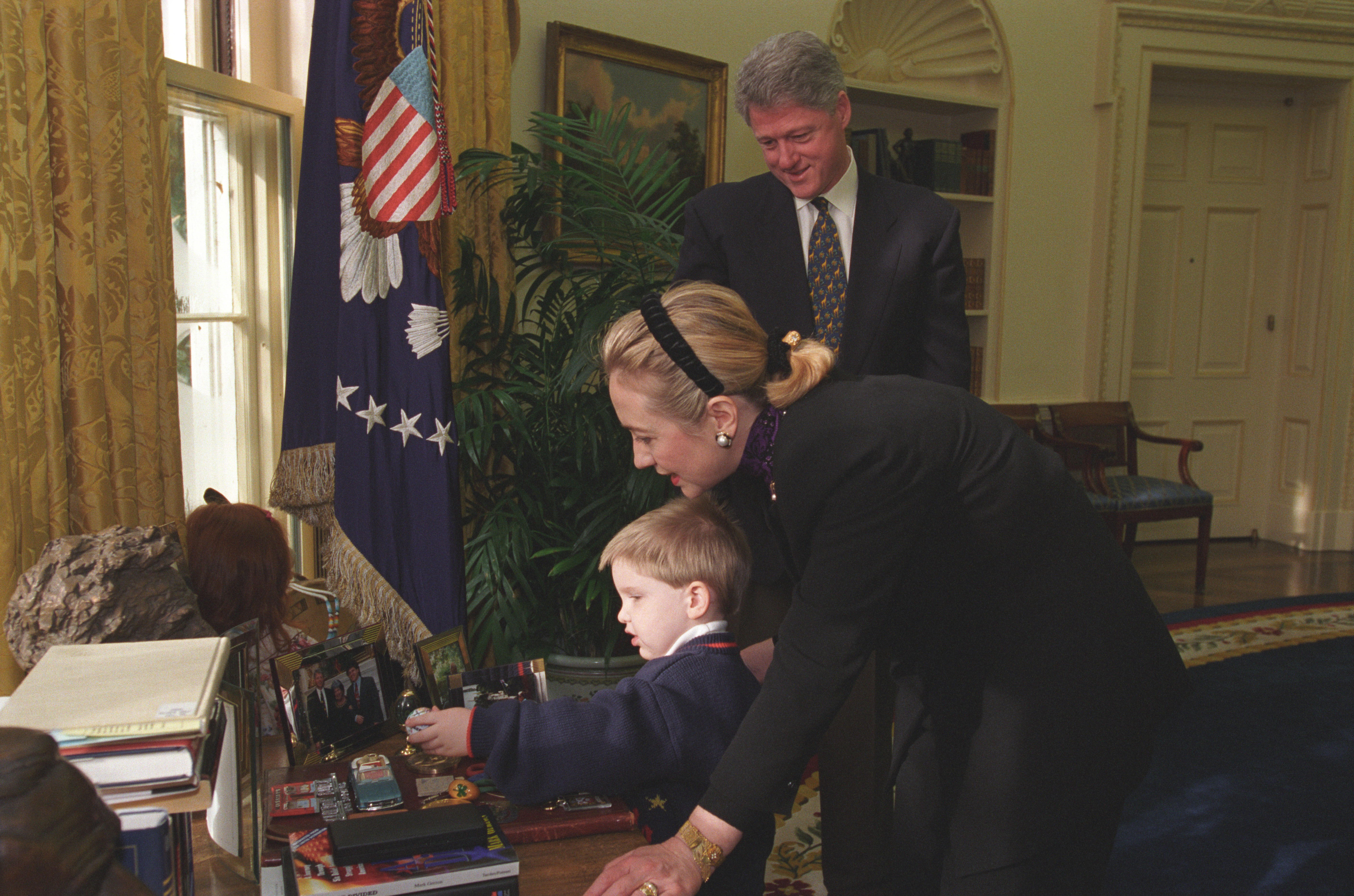 President Clinton and First Lady Hillary Rodham Clinton show photos and other items in the Oval Office to Brendon Denny who was injured in the bombing of the Murrah Federal Building in Oklahoma City. They Denny family were guests at the President's Radio Address