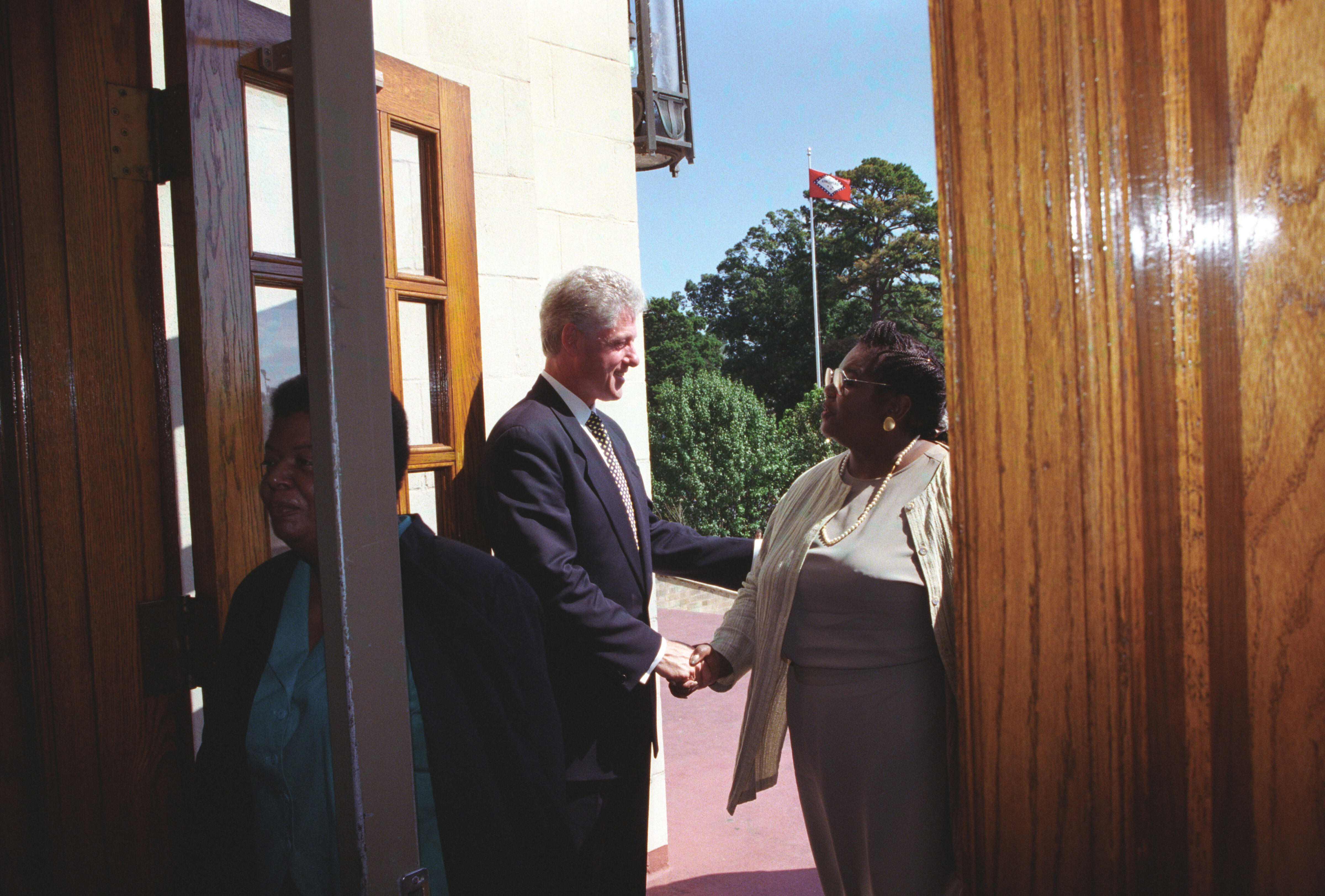 President Clinton holds the door open to Central High and greets Melba Pattillo Beals as she enters the school