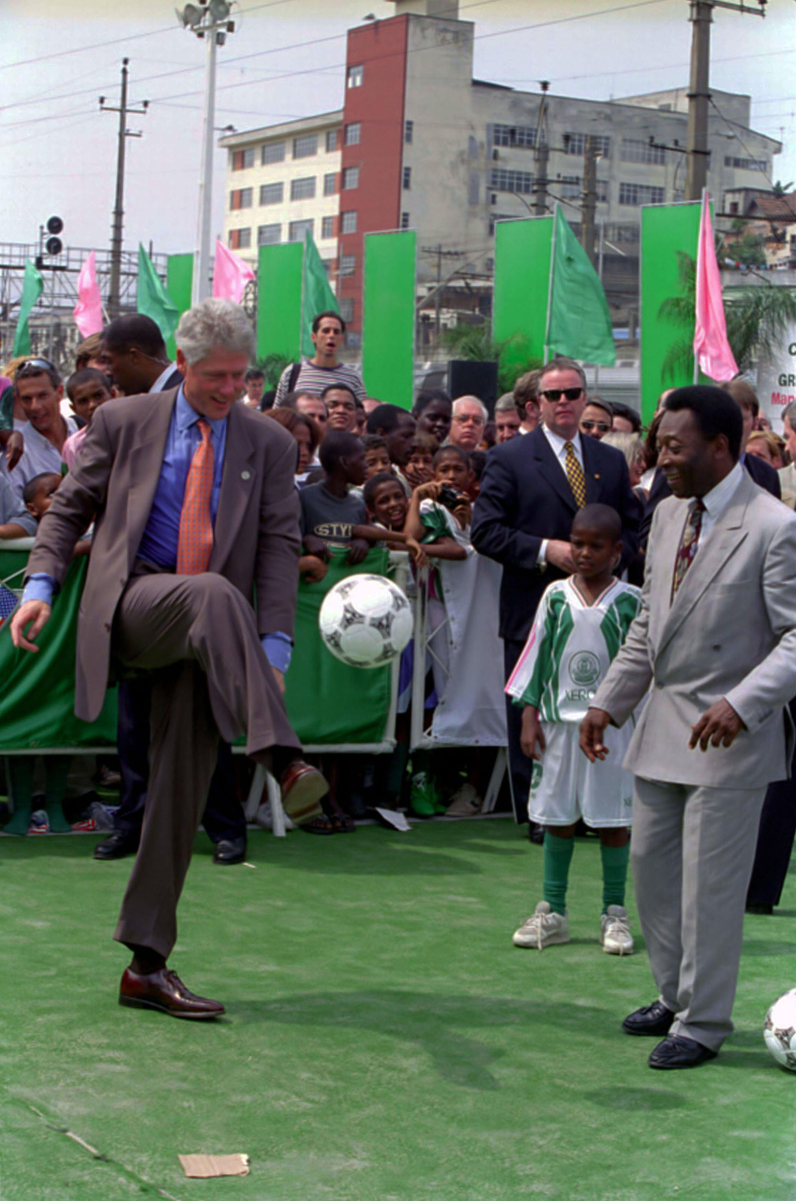 President William J. Clinton kicking a soccer ball in front of Former Professional Soccer Player Pele Edises at Mangueira School in Rio De Janeiro, Brazil