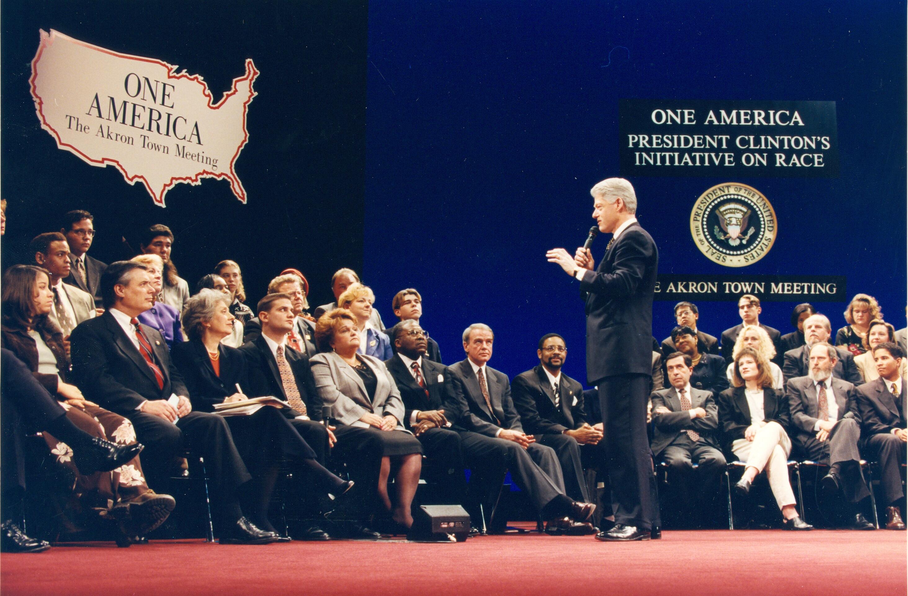 President Clinton stands addressing a sitting crowd of attendees in a Town Hall meeting concerning the President's National Discussion on Race at the E.J. Thomas Performing Arts Hall